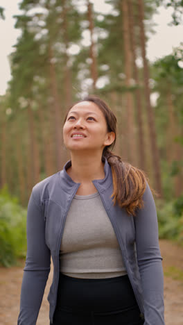 Video-Vertical-De-Una-Mujer-Vestida-Con-Ropa-Deportiva-Haciendo-Ejercicio,-Mirando-A-Su-Alrededor,-Caminando-Por-Un-Sendero-En-El-Bosque,-Disfrutando-De-La-Paz-Y-La-Belleza-De-La-Naturaleza,-Filmado-En-Tiempo-Real-1